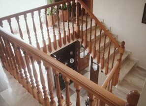 Een houten trap met een leuning, die uitkomt op een plateau met plantenpotten.
