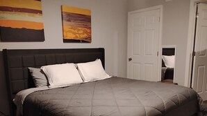 A bedroom with a large bed, a door, and two paintings on the wall. - Relaxing 1BR Near Downtown, TMC, NRG & Astros (Houston)