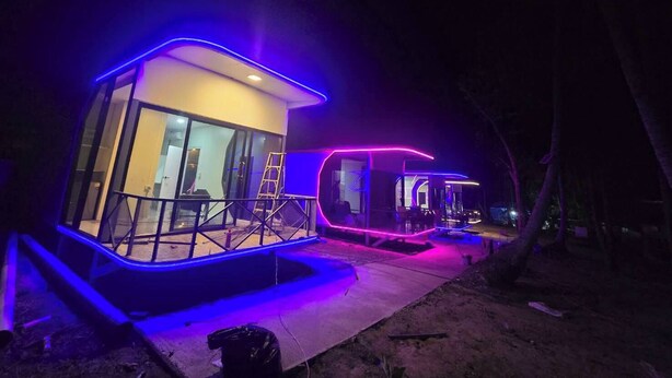 Two modern, illuminated structures with glass walls, a metal railing, and a concrete base. - Avata Resort Koh Phangan (Ko Pha-ngan)