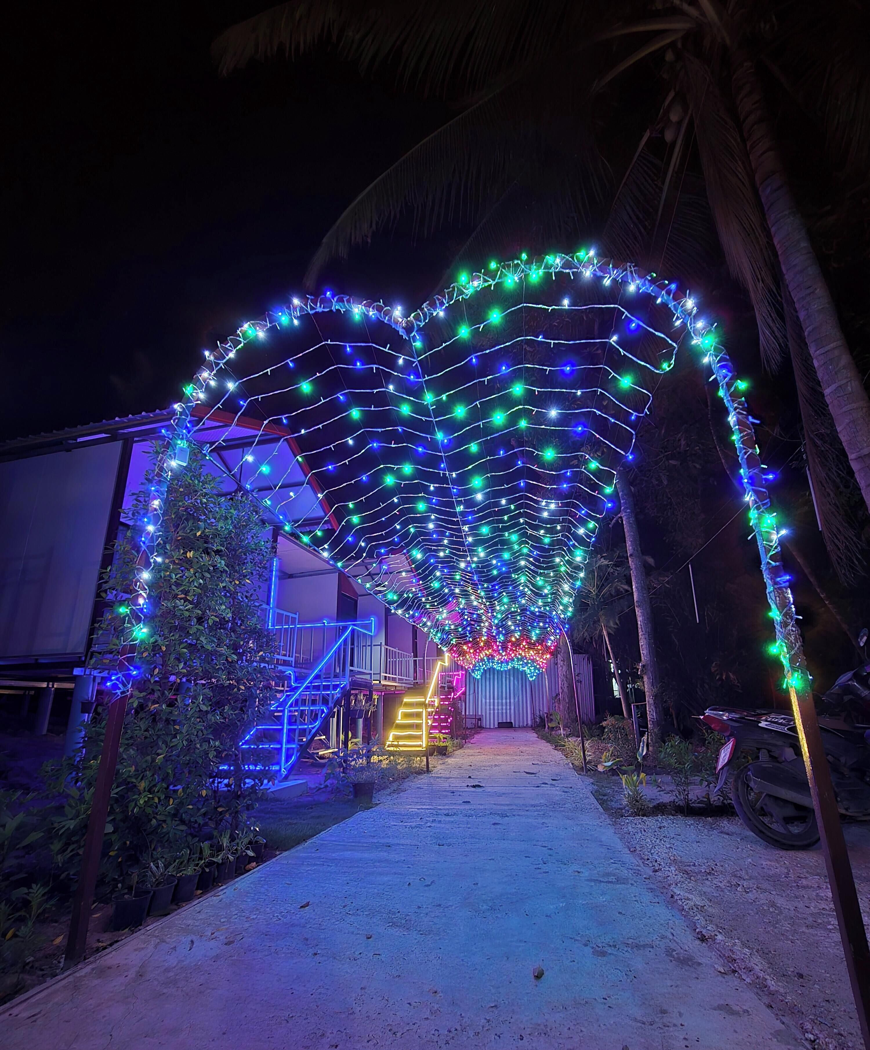 A pathway leading to a building with a heart-shaped light installation overhead.