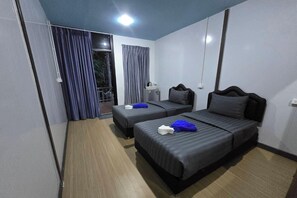 Une chambre d’hôtel avec deux lits, une petite table, une chaise, une fenêtre avec des rideaux et une porte.