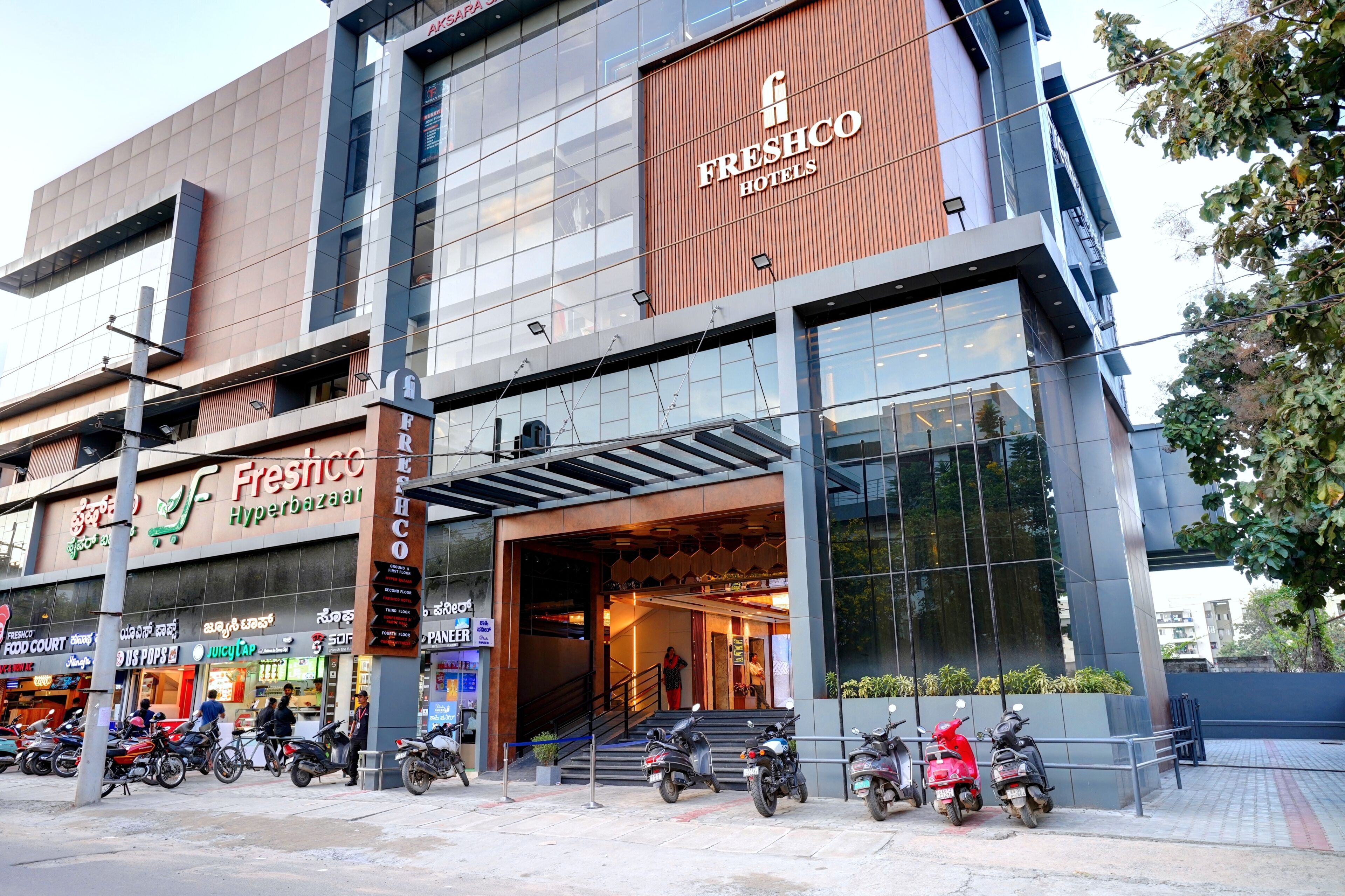 En modern byggnad med skyltar för Freshco Hyperbazaar och Freshco Hotels.