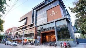 A modern hotel with a large glass facade, a visible entrance, and a sign for 'Freshco Hotels.'