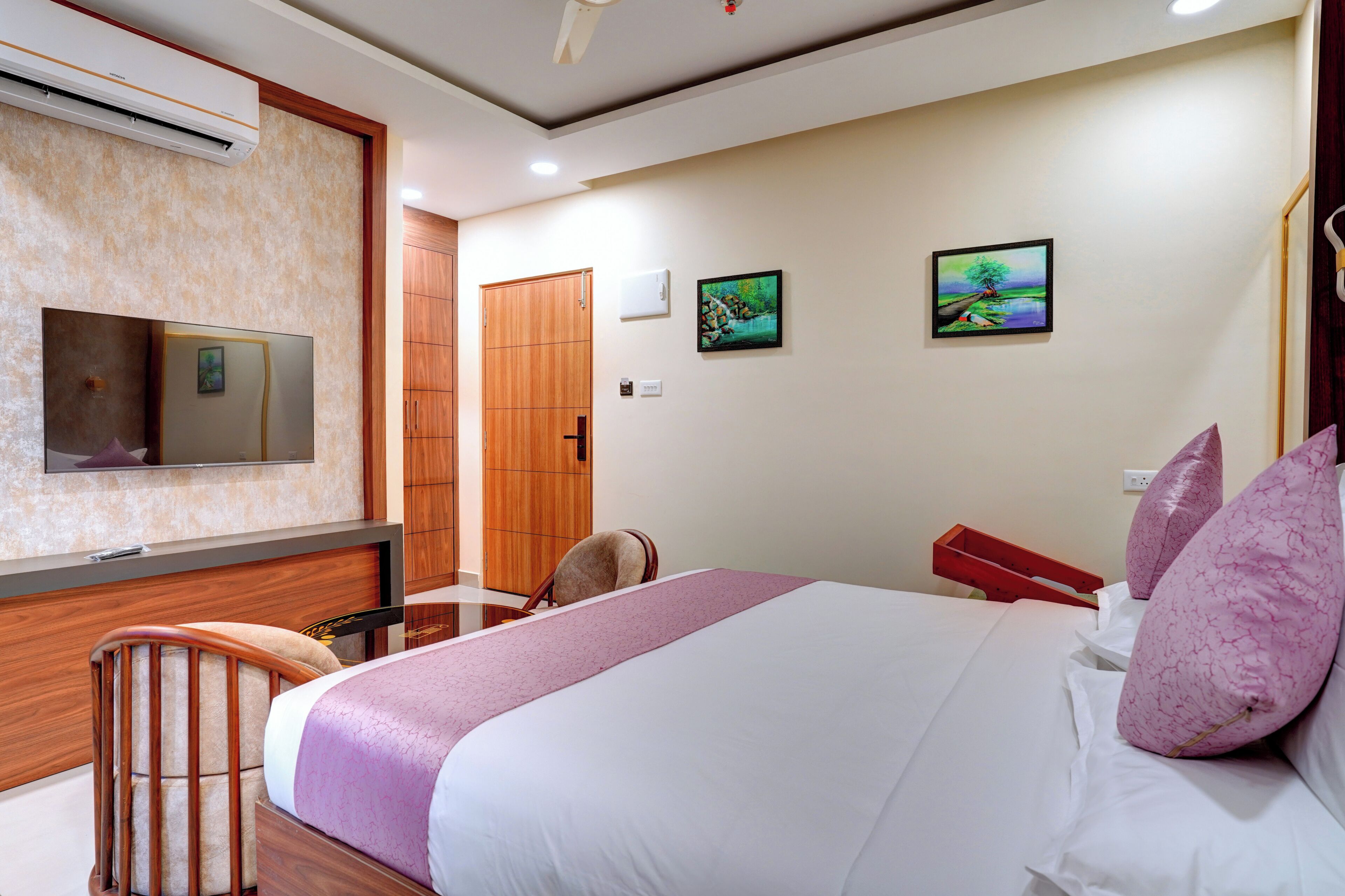 A hotel room with a bed, a chair, a TV, and a wardrobe.