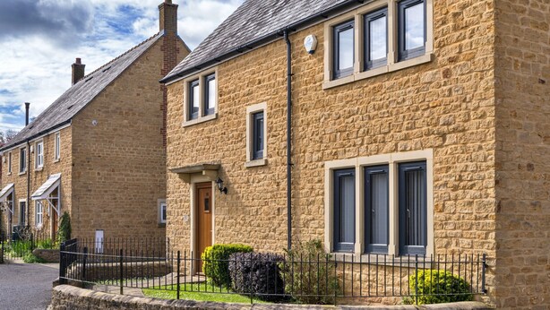 A stone house with a front door, windows, and a small garden.