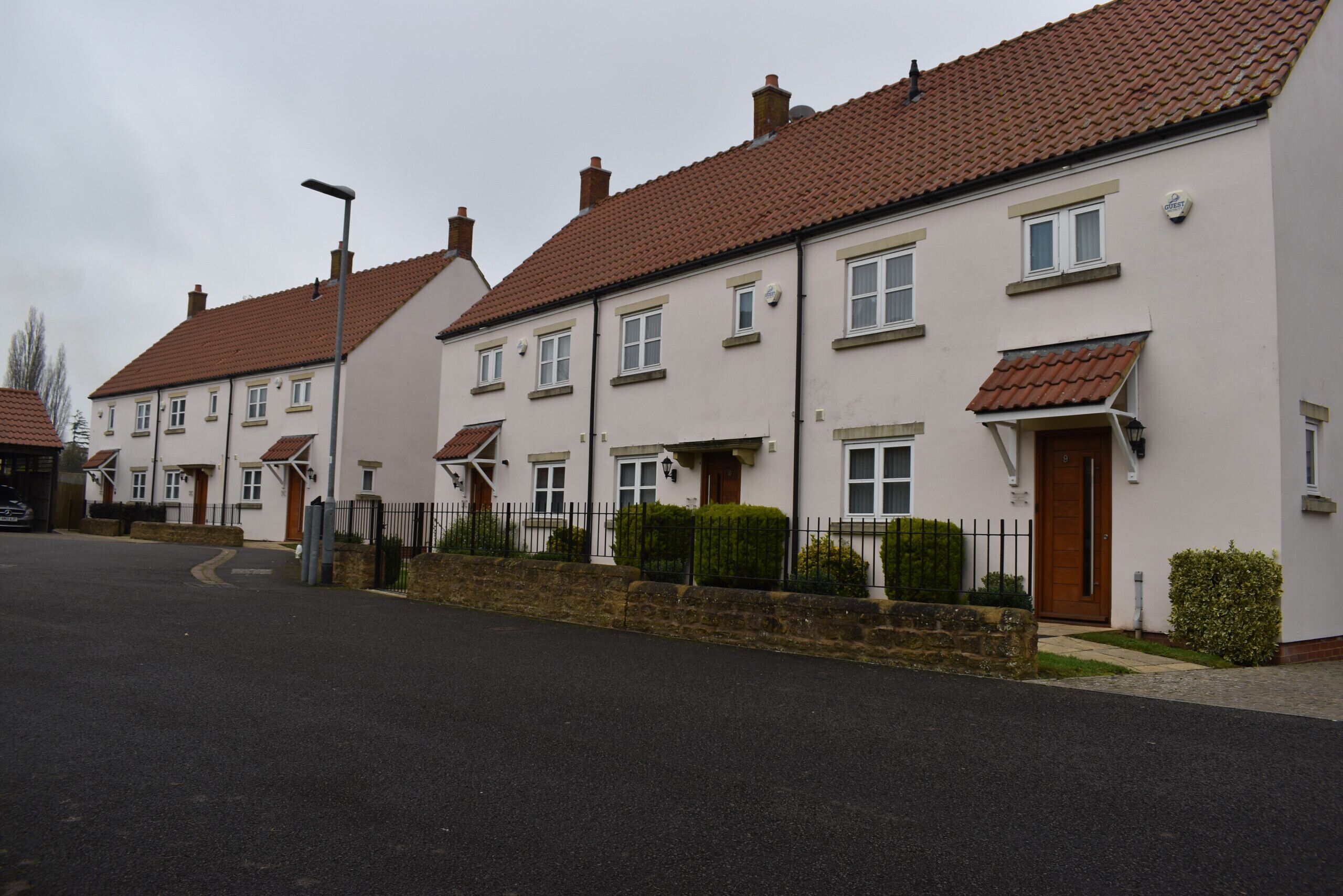 A row of terraced houses with a paved driveway and a street lamp.