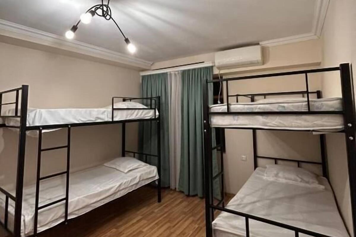 A bunk room with two bunk beds, a ceiling light, and an air conditioning unit.