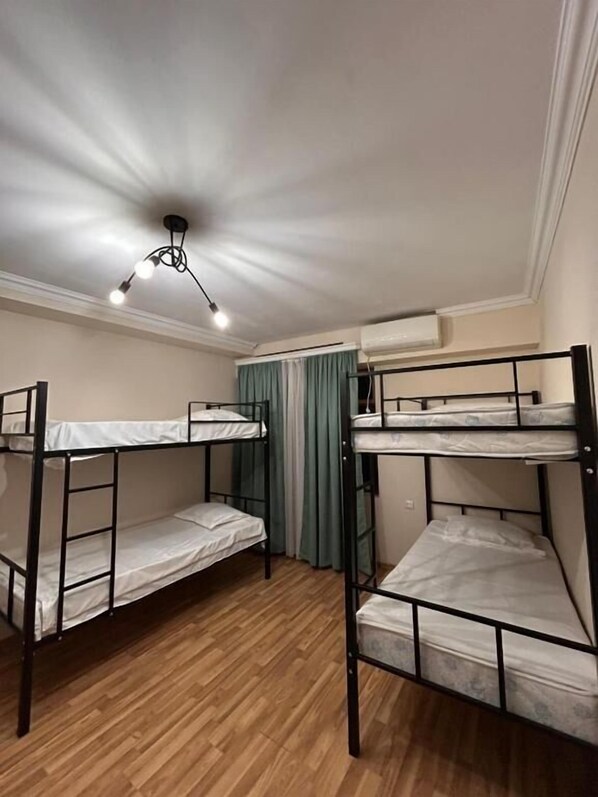 A bunk room with two bunk beds, a ceiling light, and an air conditioning unit. - Ezo hostel (Tbilisi)