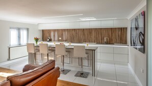 Une cuisine moderne dotée d’un îlot central, de tabourets de bar et d’un coin repas avec un canapé.
