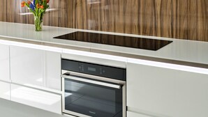 Une cuisine moderne dotée d’un four encastré, d’une plaque de cuisson en verre et d’un crédence en bois.