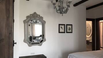 Een slaapkamer met een grote, versierde spiegel, een kroonluchter en twee ingelijste foto's aan de muur.