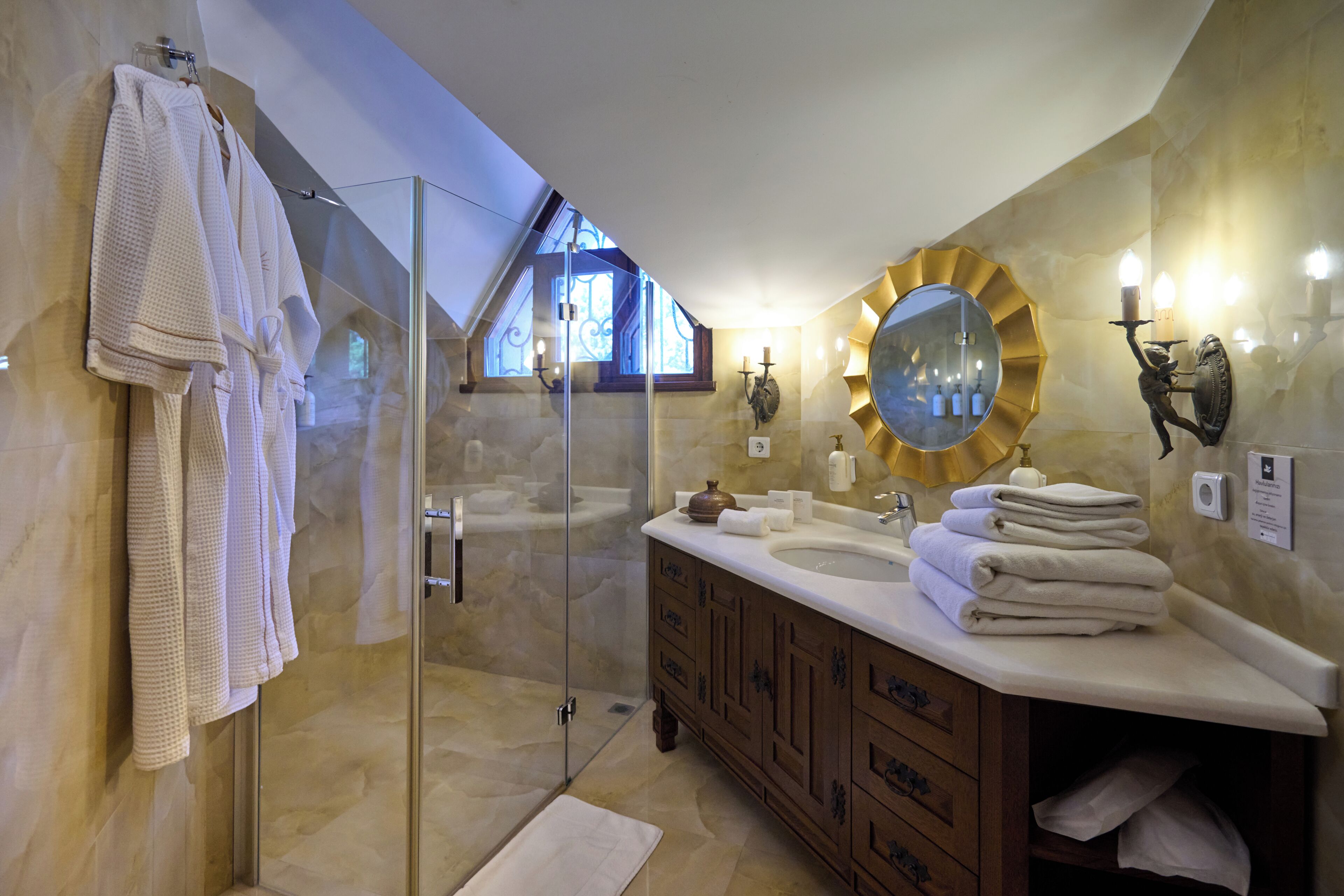 A modern bathroom with a glass-enclosed shower, a vanity with a large mirror, and towels neatly stacked.