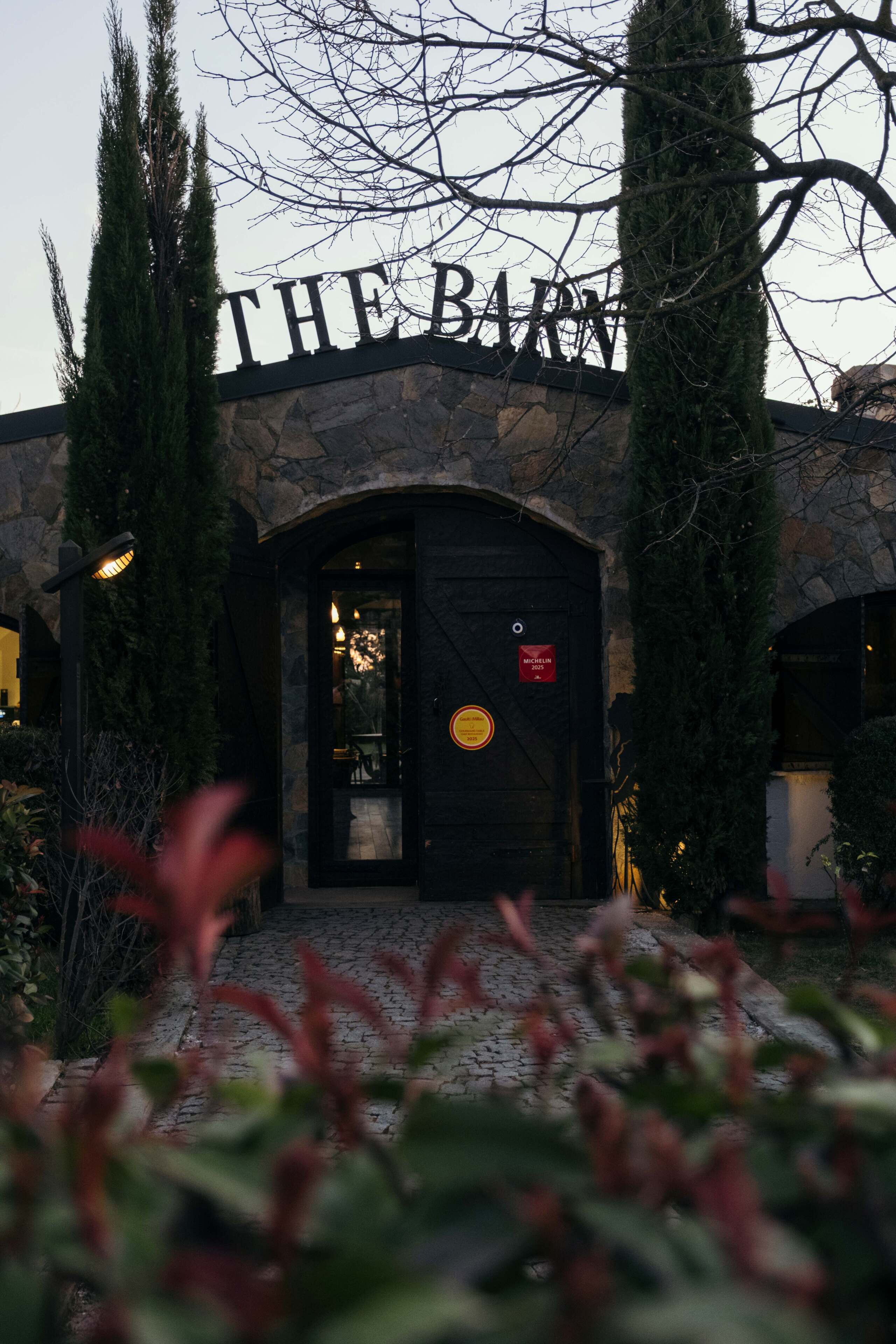 Un edificio con fachada de piedra y un letrero que dice 'THE BARN'.
