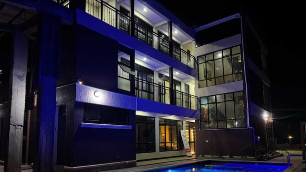 A multi-story hotel with a swimming pool, balconies, and large windows. - WYNE'S MINI SUITE (Mbale)