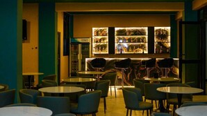 A bar area with multiple tables and chairs, a minibar, and a Solstar refrigerator. - WYNE'S MINI SUITE (Mbale)