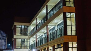 A multi-story hotel with balconies, large windows, and a well-lit entrance. - WYNE'S MINI SUITE (Mbale)