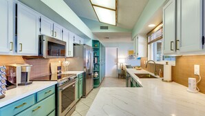 Uma cozinha moderna com armários brancos, bancada de mármore e eletrodomésticos de aço inoxidável.