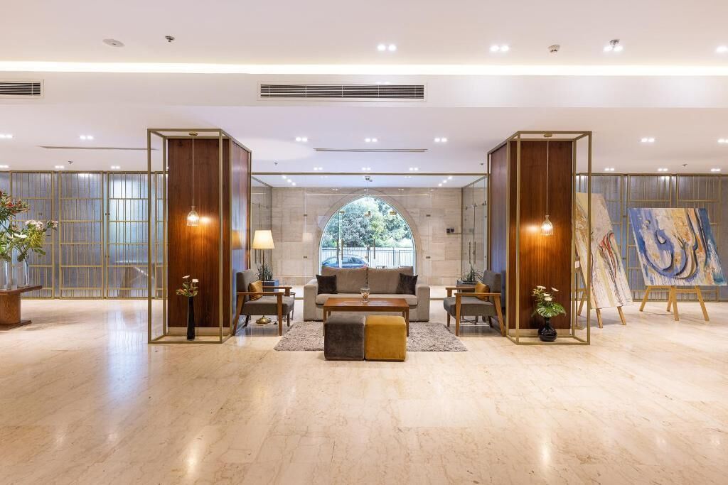 A spacious lobby with a central seating area, a large window, and a painting on display.