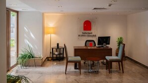 A hotel reception area with a desk, chairs, a lamp, and a sign for 'SuiteSpot ICONIA Zamalek.' - ICONIA Zamalek (Zamalek)