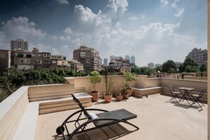 A rooftop terrace with a lounge chair, a small table, and potted plants. - ICONIA Zamalek (Zamalek)
