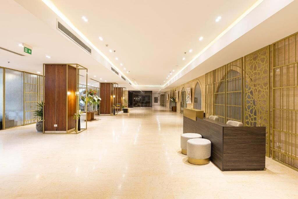 A hotel lobby with a reception desk, seating area, and decorative elements.