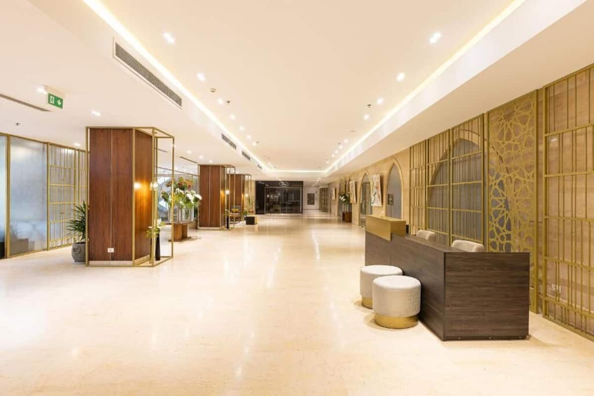 A hotel lobby with a reception desk, seating area, and decorative elements.