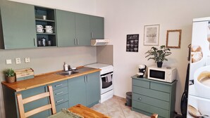 Kompakti keittiö, jossa on pesuallas, liesi, mikroaaltouuni ja kaapit.