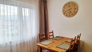 Ruokailutila, jossa on puinen pöytä, neljä tuolia ja seinälle kiinnitetty kello.