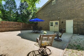 A patio area with a brick wall, outdoor furniture, and a blue umbrella.