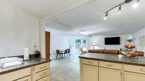 Een keuken met een aanrecht, kastjes en een eethoek met een tafel en stoelen.