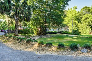 A residential area with a well-maintained lawn, a palm tree, and a house with a brick facade.