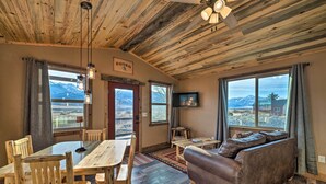 En rustik inredning med ett träpanelat tak, en soffa, en tv och en matplats med stolar och ett bord.