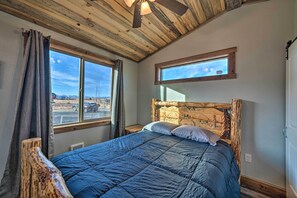 Ein Schlafzimmer mit einem großen Bett, einem Holzkopfende, zwei Fenstern und einem Deckenventilator.