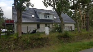 A house with a sloped roof, a small window, and a fenced yard. - Holiday Home 'Waldwiese' for 8 Guests (110 m²) in Fuhlendorf OT Bodstedt (Boddenküste McPomm) (Fuhlendorf)