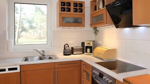A modern kitchen with a built-in oven, a coffee maker, and a kettle. - Holiday Home 'Waldwiese' for 8 Guests (110 m²) in Fuhlendorf OT Bodstedt (Boddenküste McPomm) (Fuhlendorf)