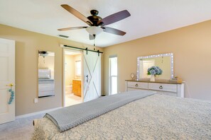 A bedroom with a bed, a ceiling fan, a dresser, a mirror with lights, and a door leading to another room. - Heated Pool! Extended Stay 4 Mi to Manasota Beach (Englewood)