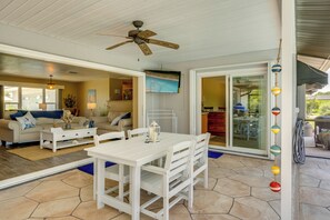 A spacious living area with a white dining table, a ceiling fan, and a large sliding glass door leading to an outdoor patio. - Heated Pool! Extended Stay 4 Mi to Manasota Beach (Englewood)
