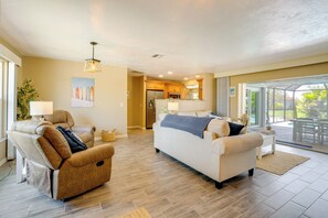 A living room with a sofa, armchair, and a dining area with a table and chairs. - Heated Pool! Extended Stay 4 Mi to Manasota Beach (Englewood)