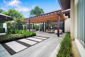 Eine moderne Außenpatio mit Pergola, Sitzbereich und angelegtem Garten.