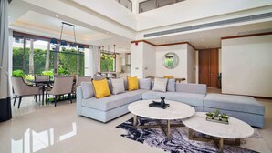 A spacious living area with a large L-shaped sofa, a dining table, and two coffee tables. - Banyan Tree Grand Residences, Four-bedroom Pool Villa (Choeng Thale)