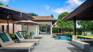 A modern outdoor pool area with lounge chairs and umbrellas. - Banyan Tree Grand Residences, Four-bedroom Pool Villa (Choeng Thale)