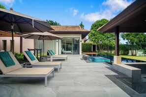 Ein moderner Poolbereich im Freien mit Liegestühlen und Sonnenschirmen.