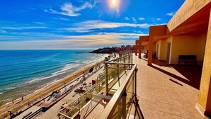 A coastal hotel with a balcony overlooking the beach and ocean.