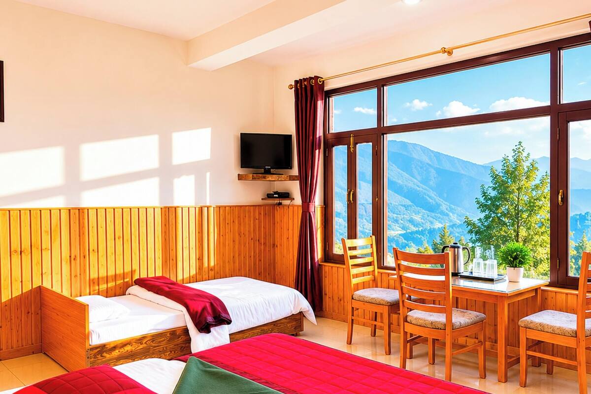 A hotel room with two beds, a TV, a table with chairs, and a view of mountains.