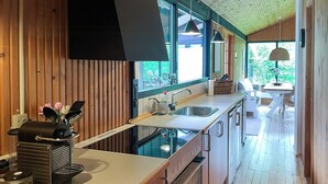 A modern kitchen with wooden walls, a built-in oven, and a large window.