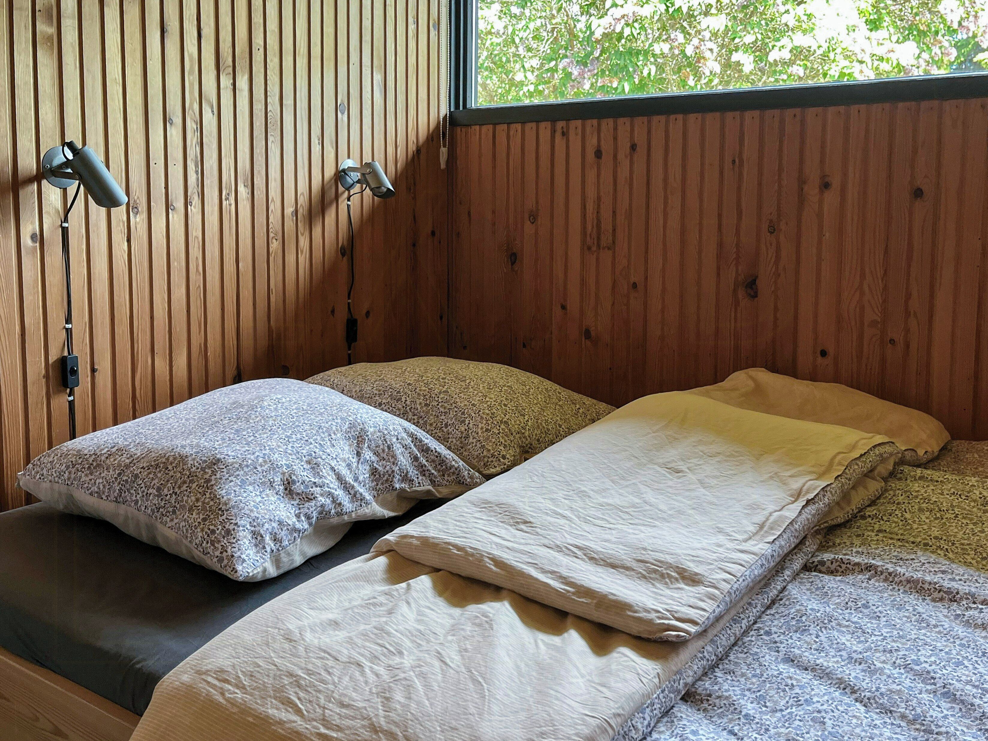 A wooden room with two beds, each with a pillow and a blanket.