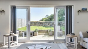 Una sala de estar moderna con un gran ventanal corredero que da a un jardín.