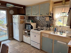 A compact kitchen with a refrigerator, microwave, stove, and sink. - Stay at "Seas the Day" in Ferry Beach, Saco, ME—an inviting 4-bedroom cottage near Camp Ellis (Saco)
