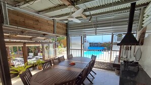 A covered outdoor dining area with a pool in the background. - Maison aux Portes du Sud Sauvage – Family Home with Pool & Hot Tub (Saint Joseph)