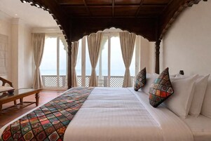 A bedroom with a large bed, a view of the sea, and a balcony with curtains.